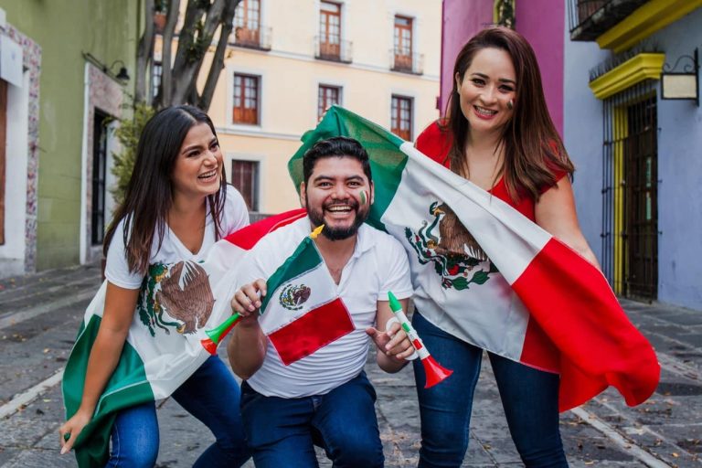 Three people celebrating with Mexican flags and party horns