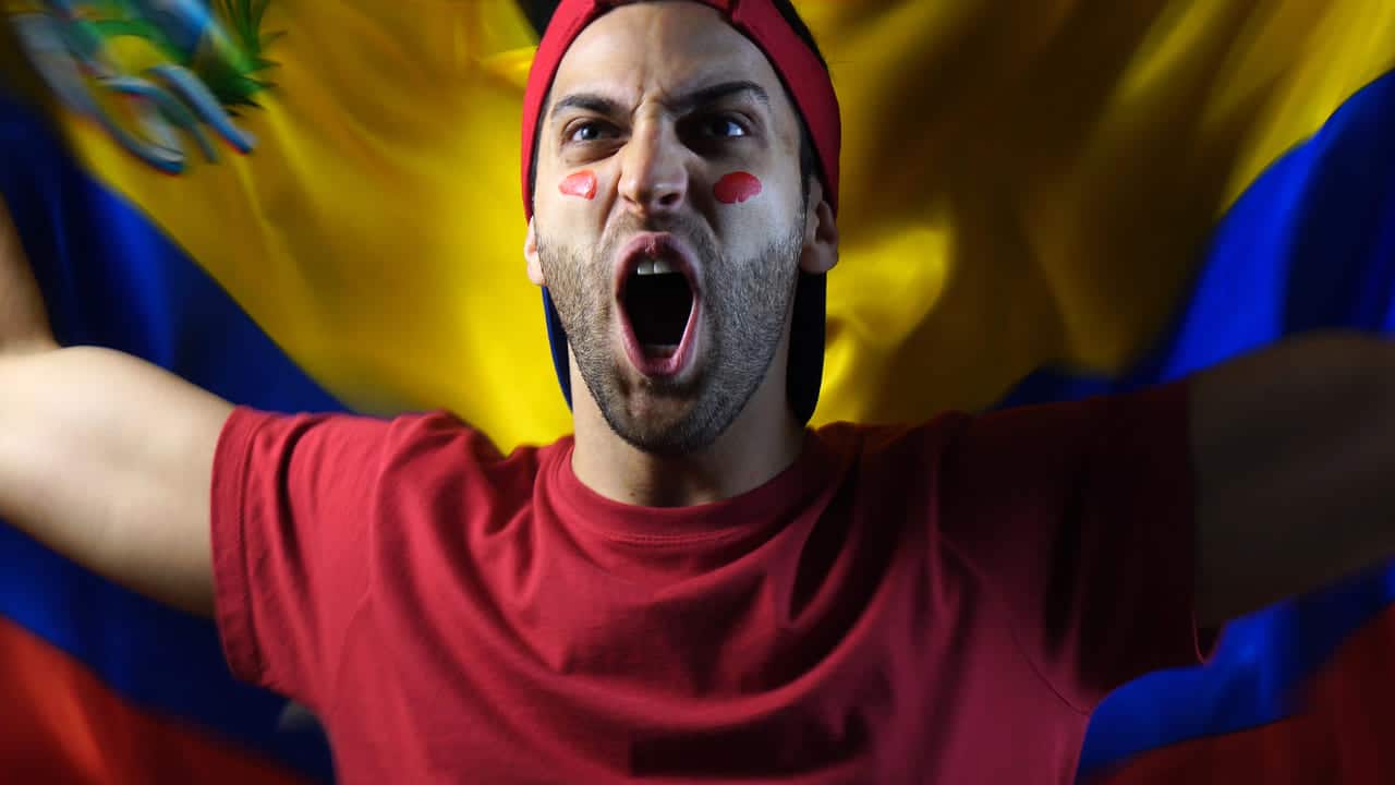 Man cheering passionately with painted face, holding a flag