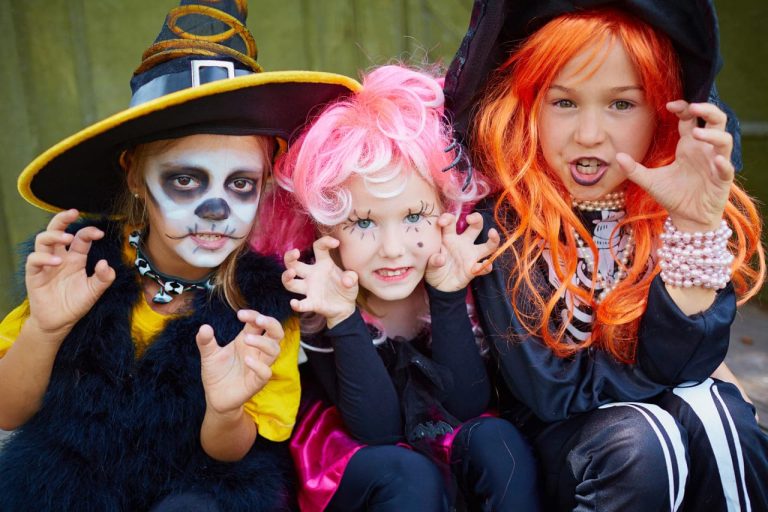 Three kids in Halloween costumes making scary faces