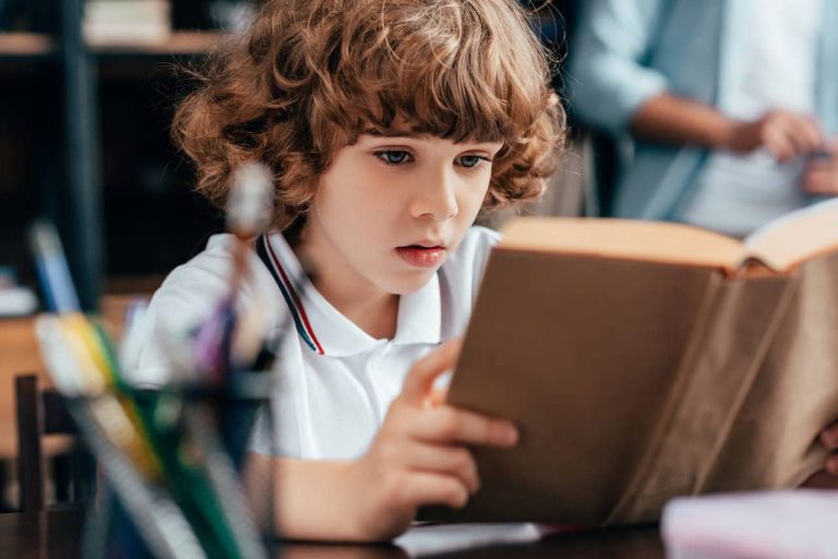 A focused young boy reading a book intently