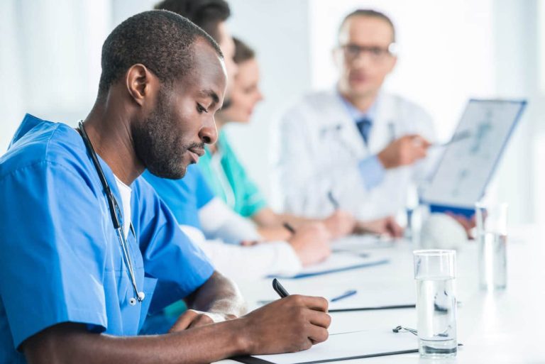 A focused medical professional taking notes during a team meeting