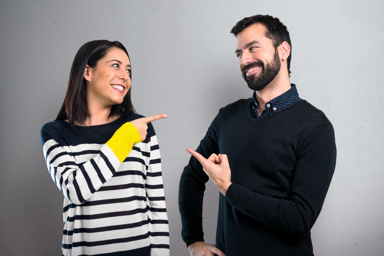 Two people pointing at each other and smiling playfully