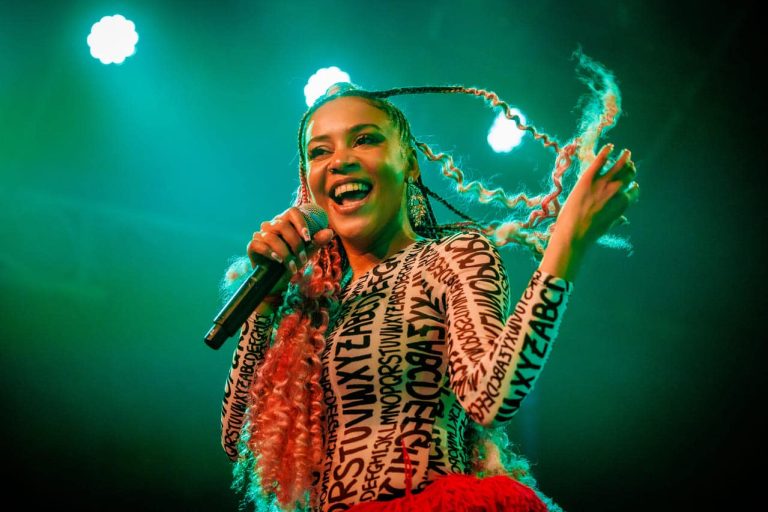 woman performing on stage holding microphone with green lighting