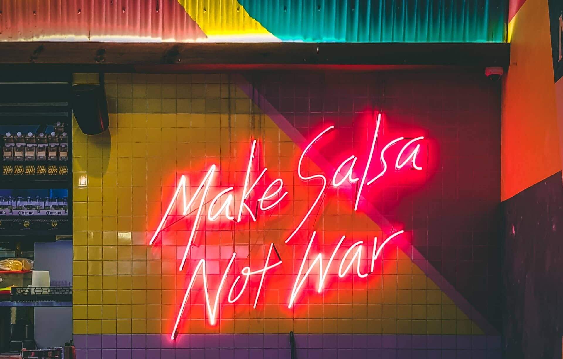 Neon sign with “Make salsa not war”