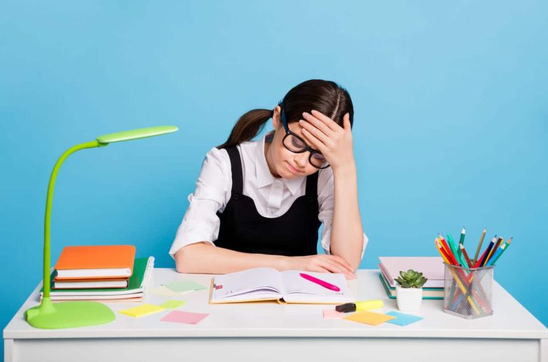 Girl in glasses looking frustrated while studying at her desk