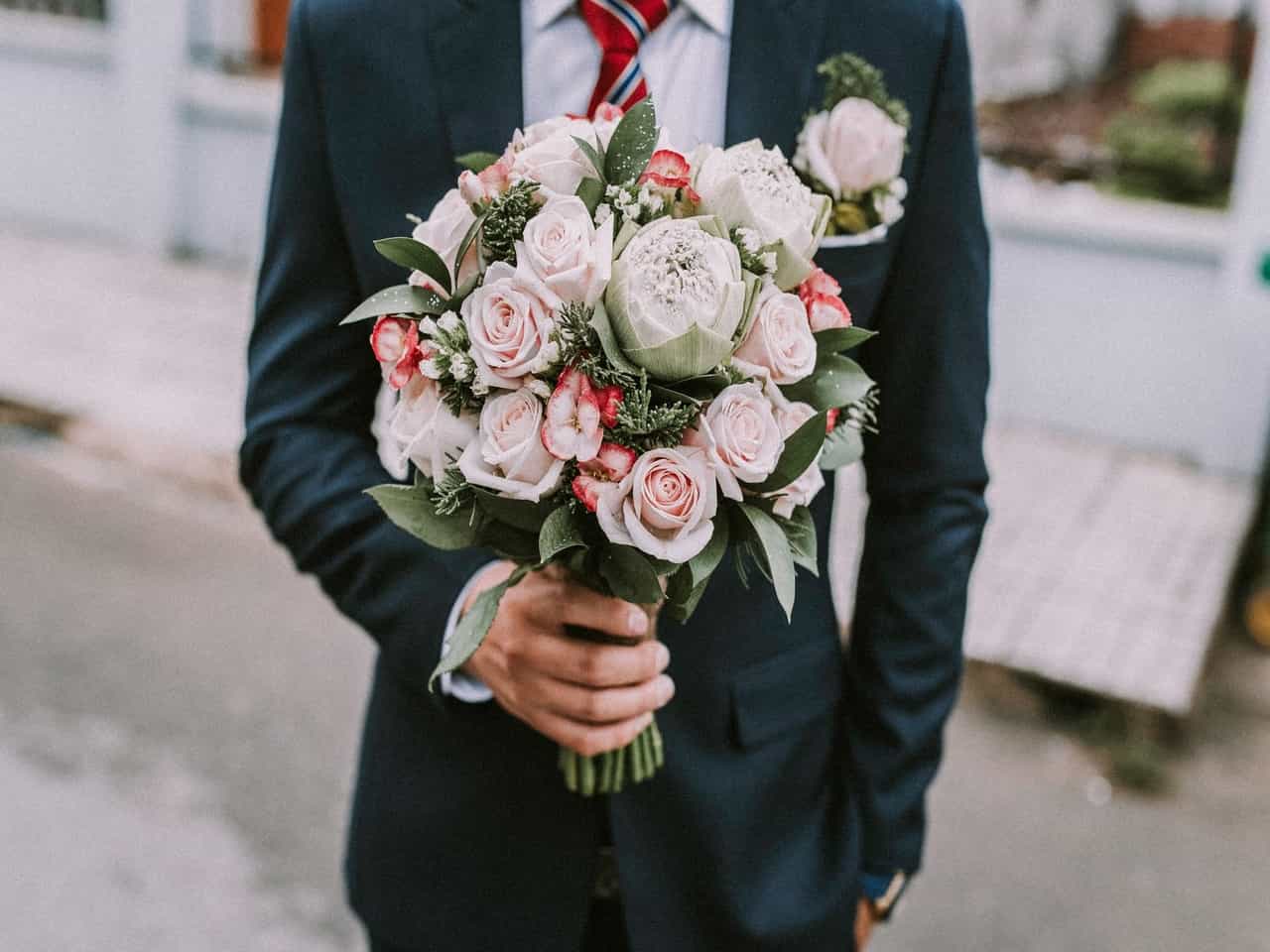 Person in suit holding a bouquet of flowers