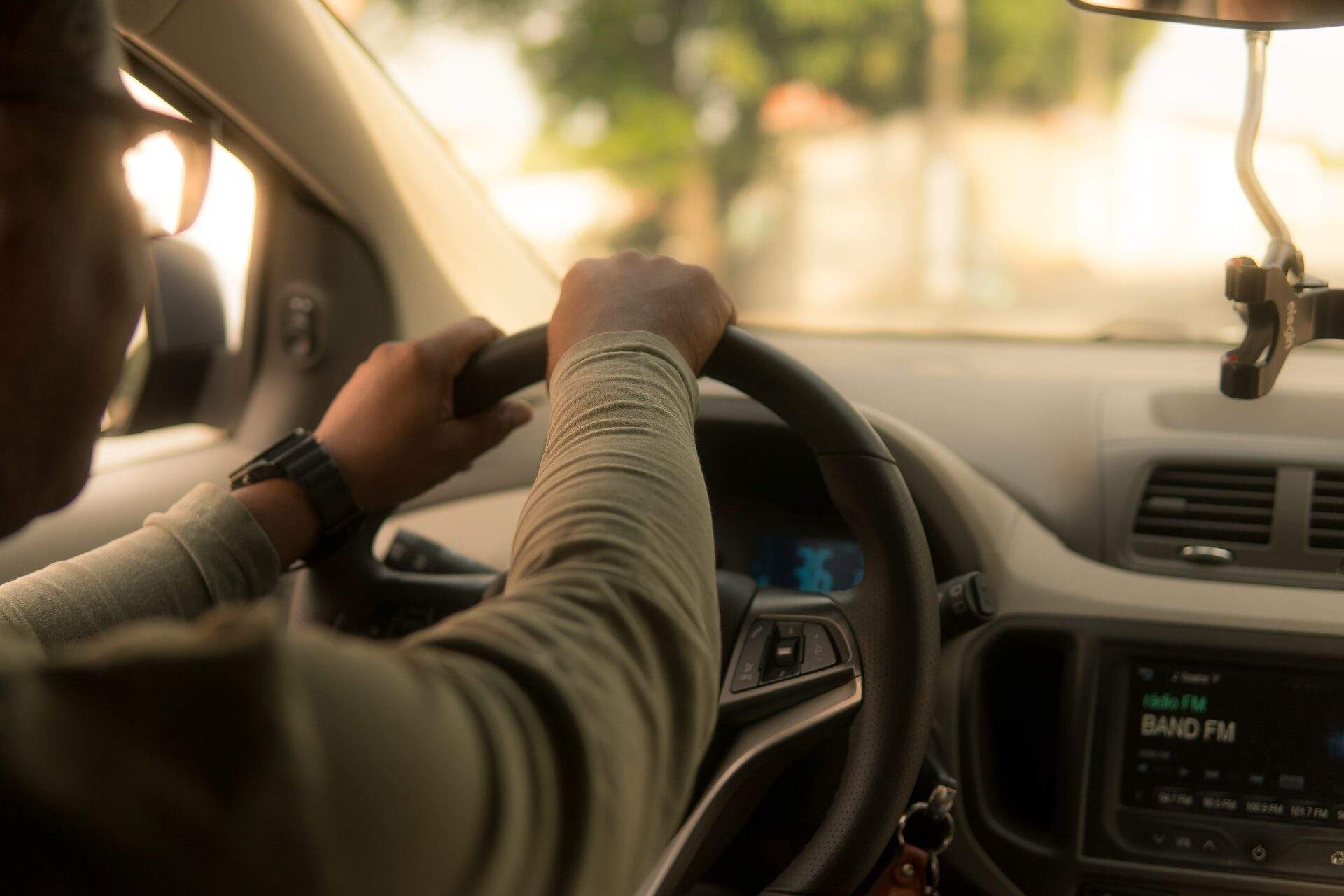 A person driving a car, gripping the steering wheel with both hands