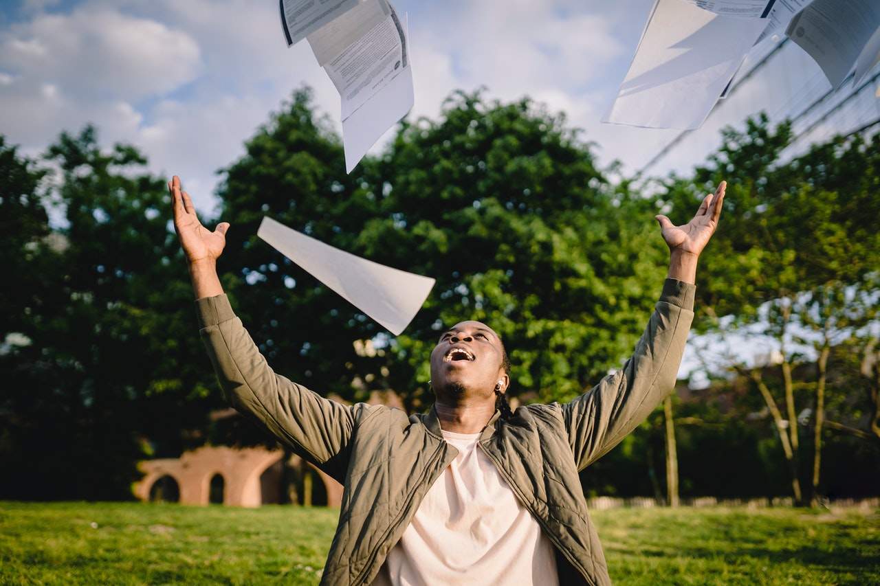 Person outdoors throwing papers in the air