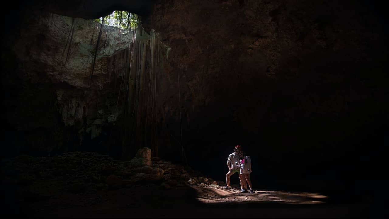 Couple standing inside a large cave with light