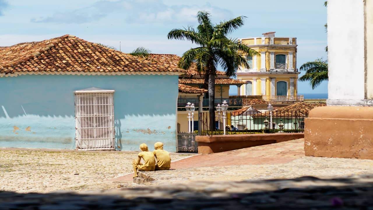 Colonial-style houses with tiled roofs and palm trees in a sunny town