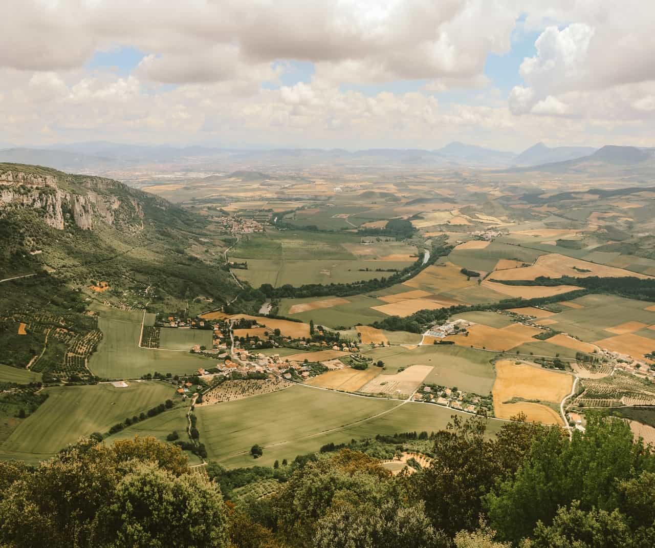 Scenic view of fields and mountains under clouds