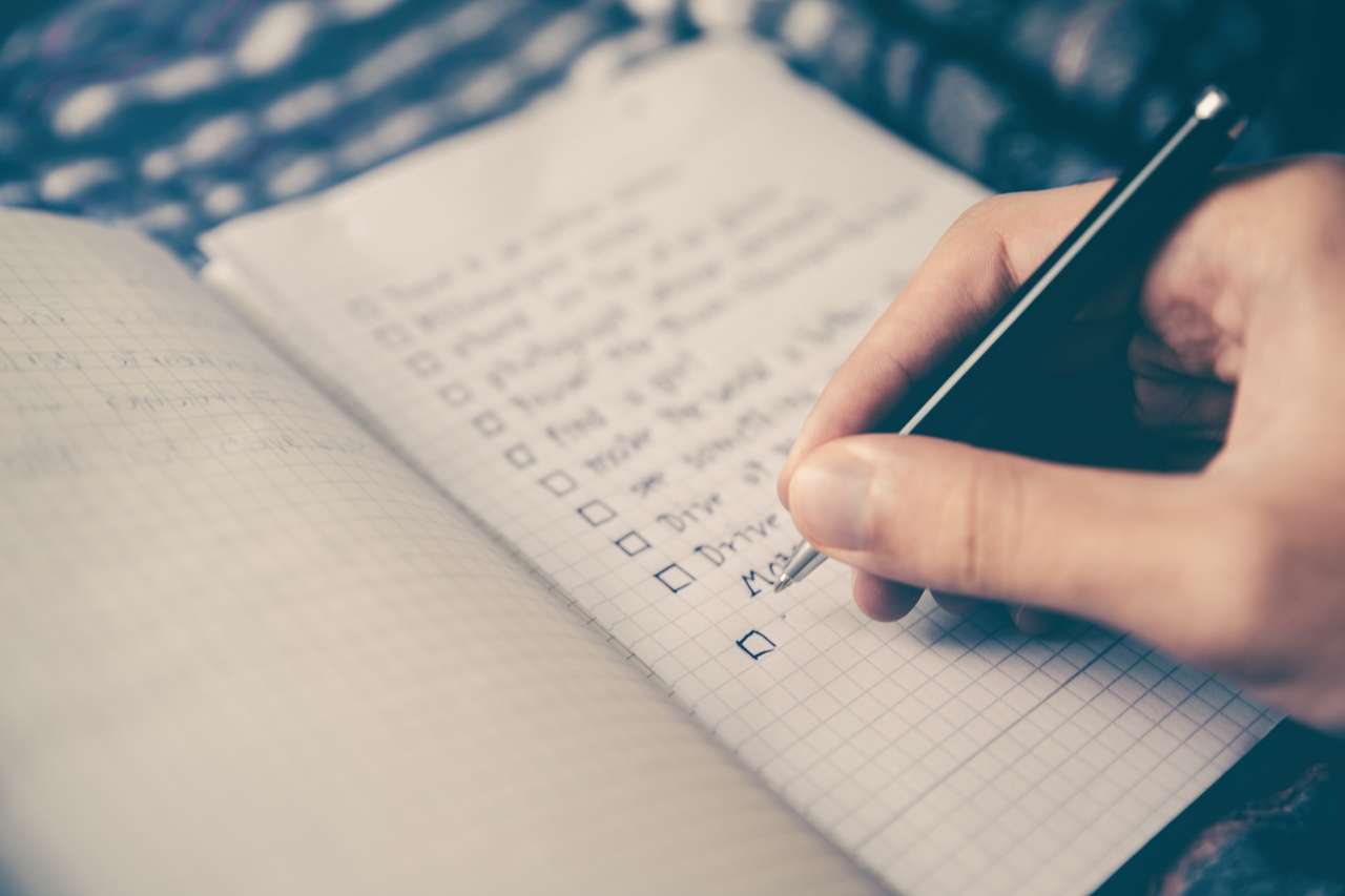 Person writing on a checklist in a notebook