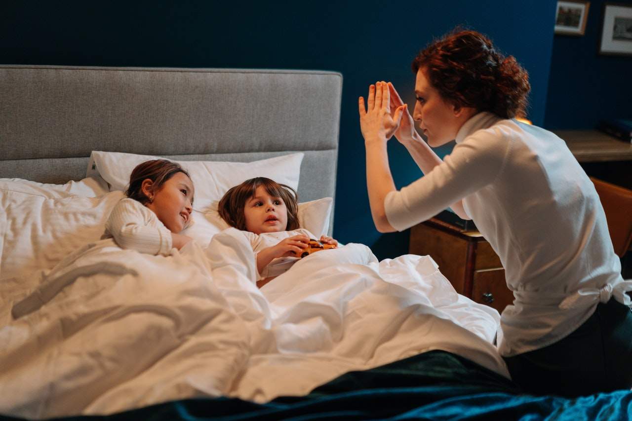 Parent telling a bedtime story to two children in bed