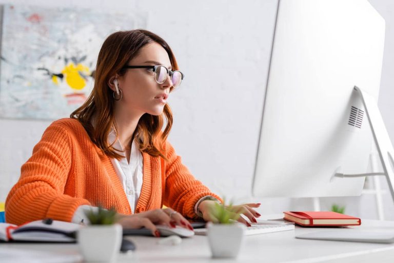A woman in glasses working on a computer