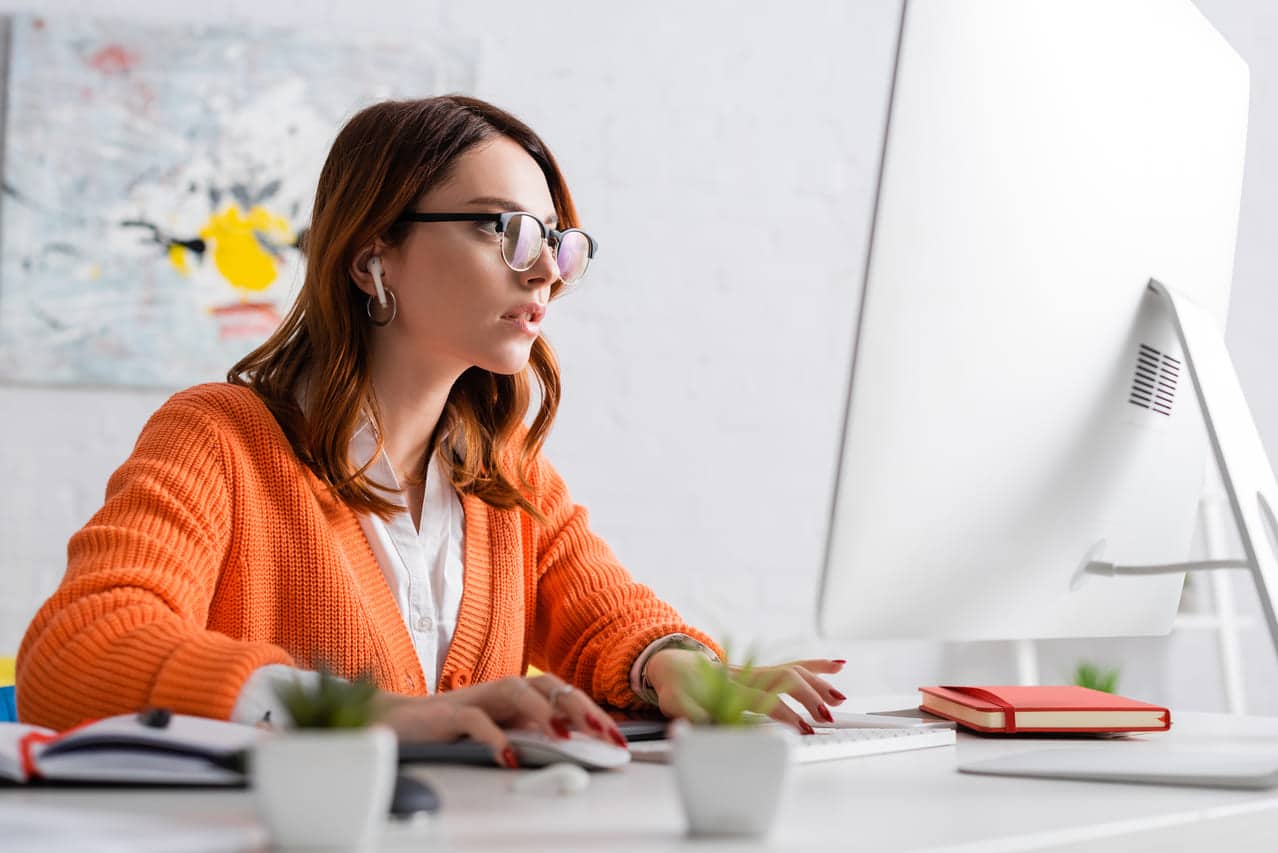 A woman in glasses working on a computer