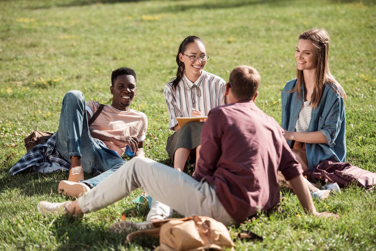 Group of friends sitting and talking together on the grass