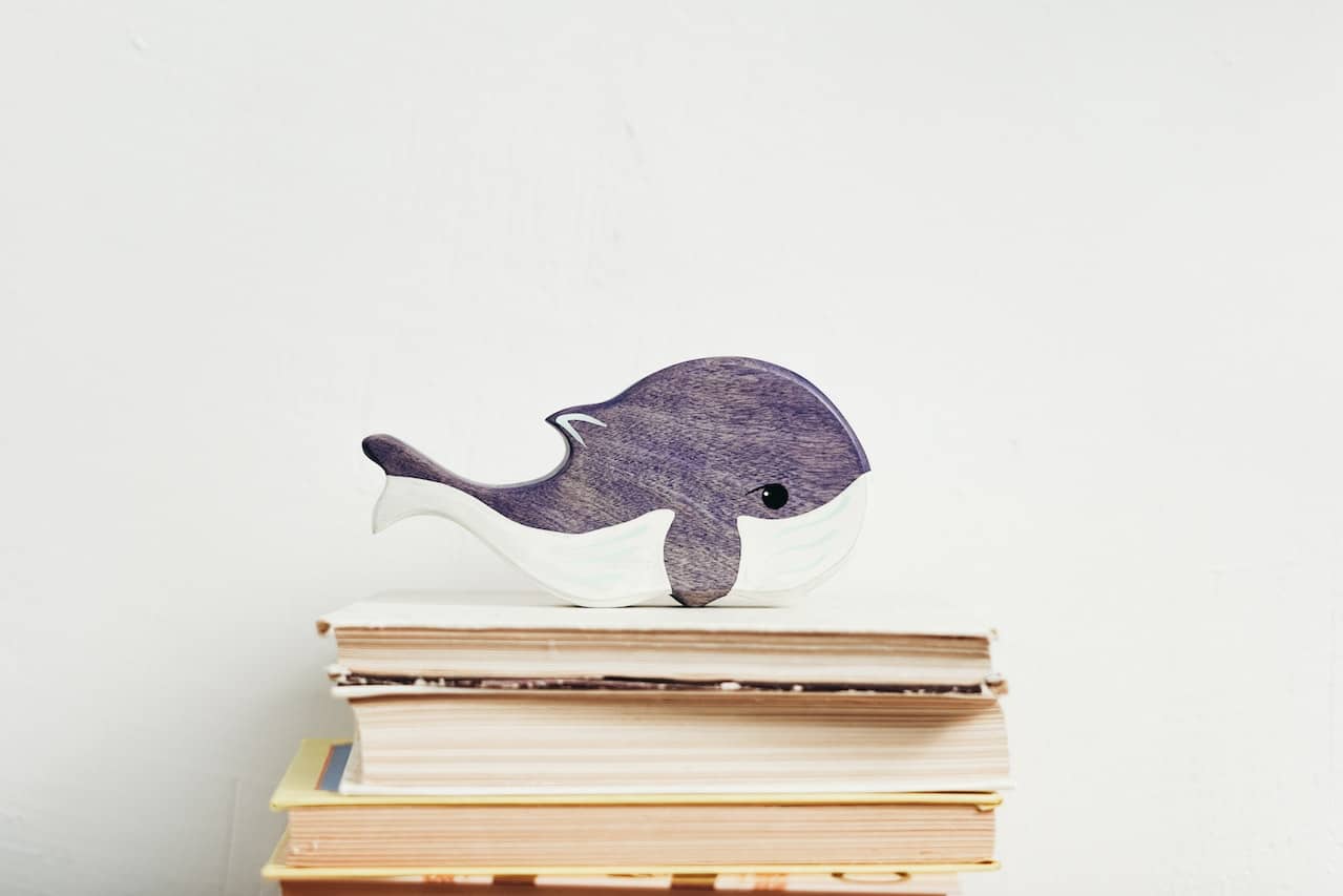 Wooden whale figurine on stacked books