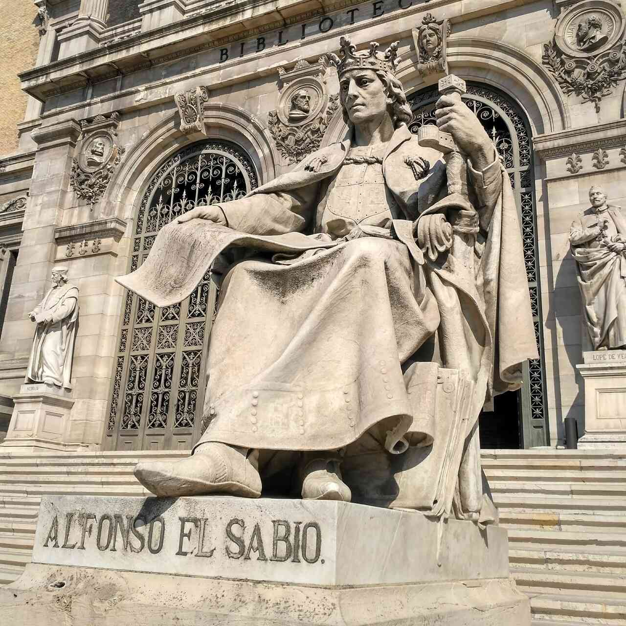 Statue of Alfonso el Sabio outside a large building