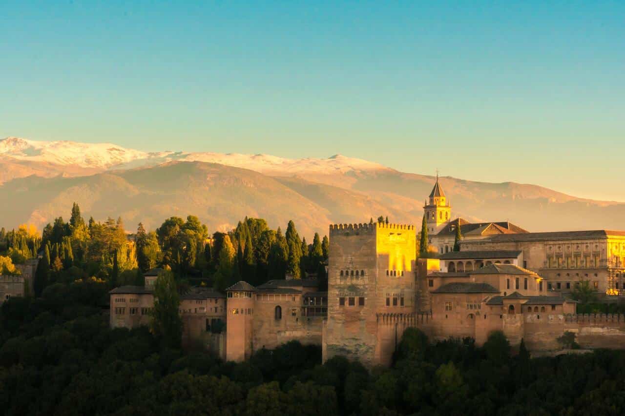 Snow-capped mountains and castle during golden hour sunlight