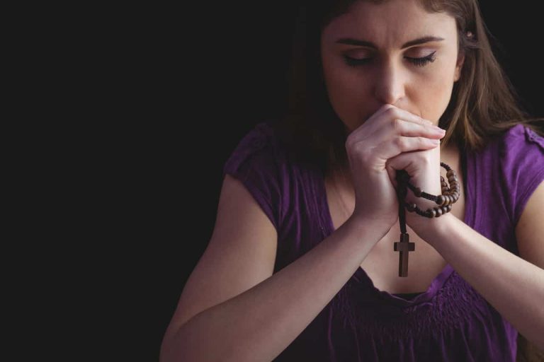Woman praying while holding a rosary