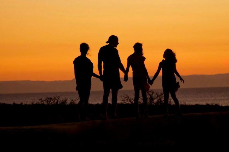 Silhouette of family holding hands at sunset
