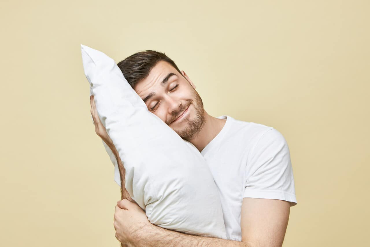 Man holding a pillow and smiling