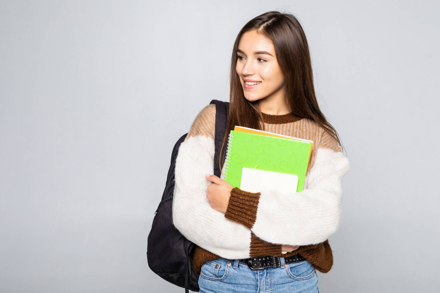 Student with a backpack holding notebooks in her arms
