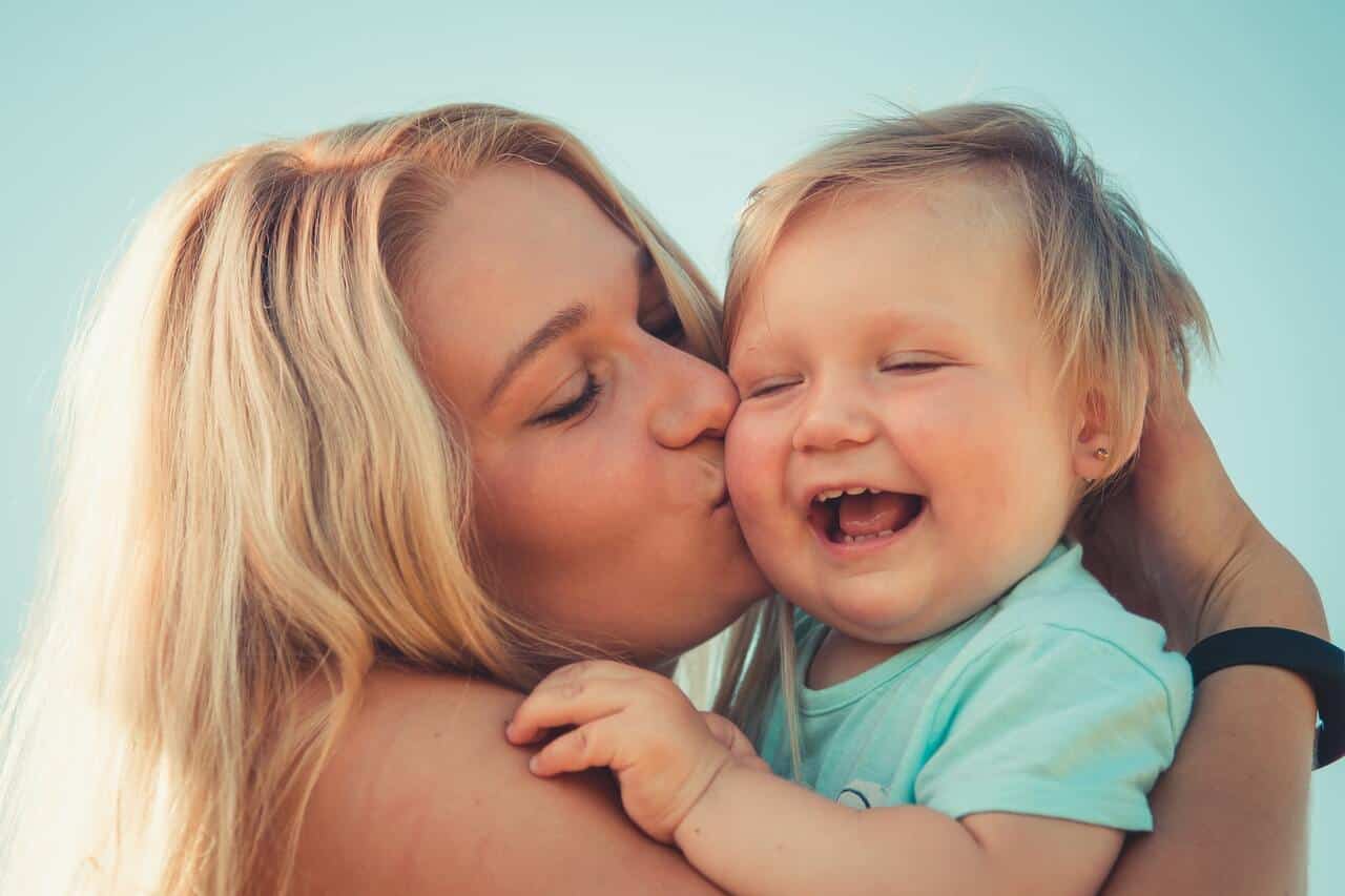 Mother kissing smiling baby in a joyful moment