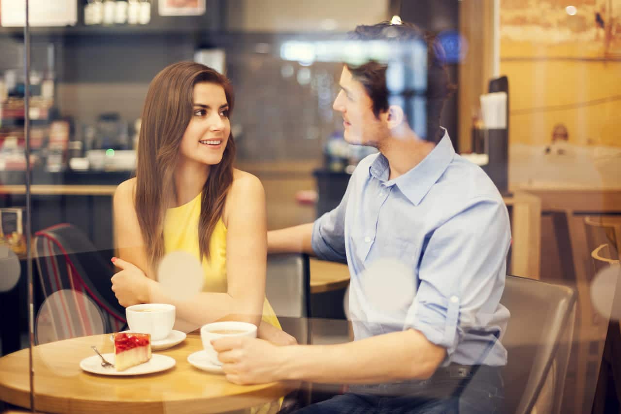 Couple enjoying coffee and dessert while talking at a cafe
