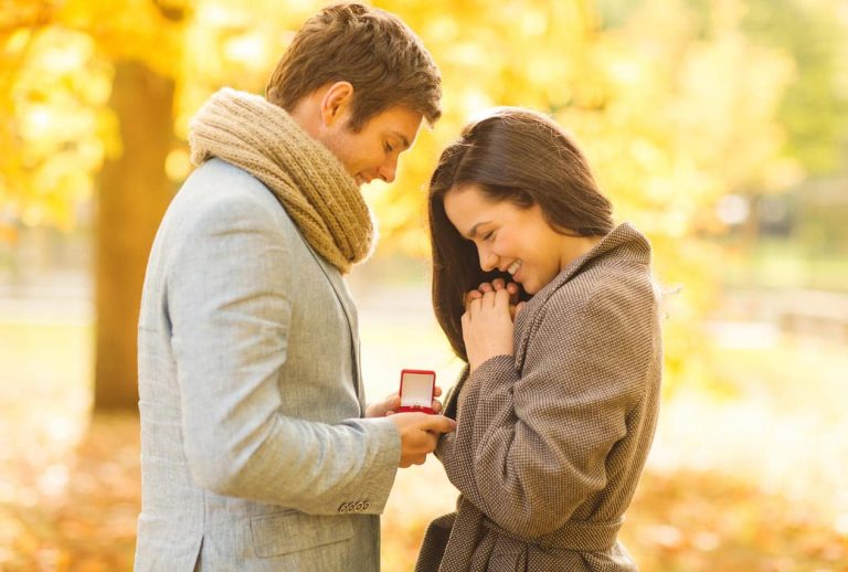 Man proposing to woman with a ring in autumn park