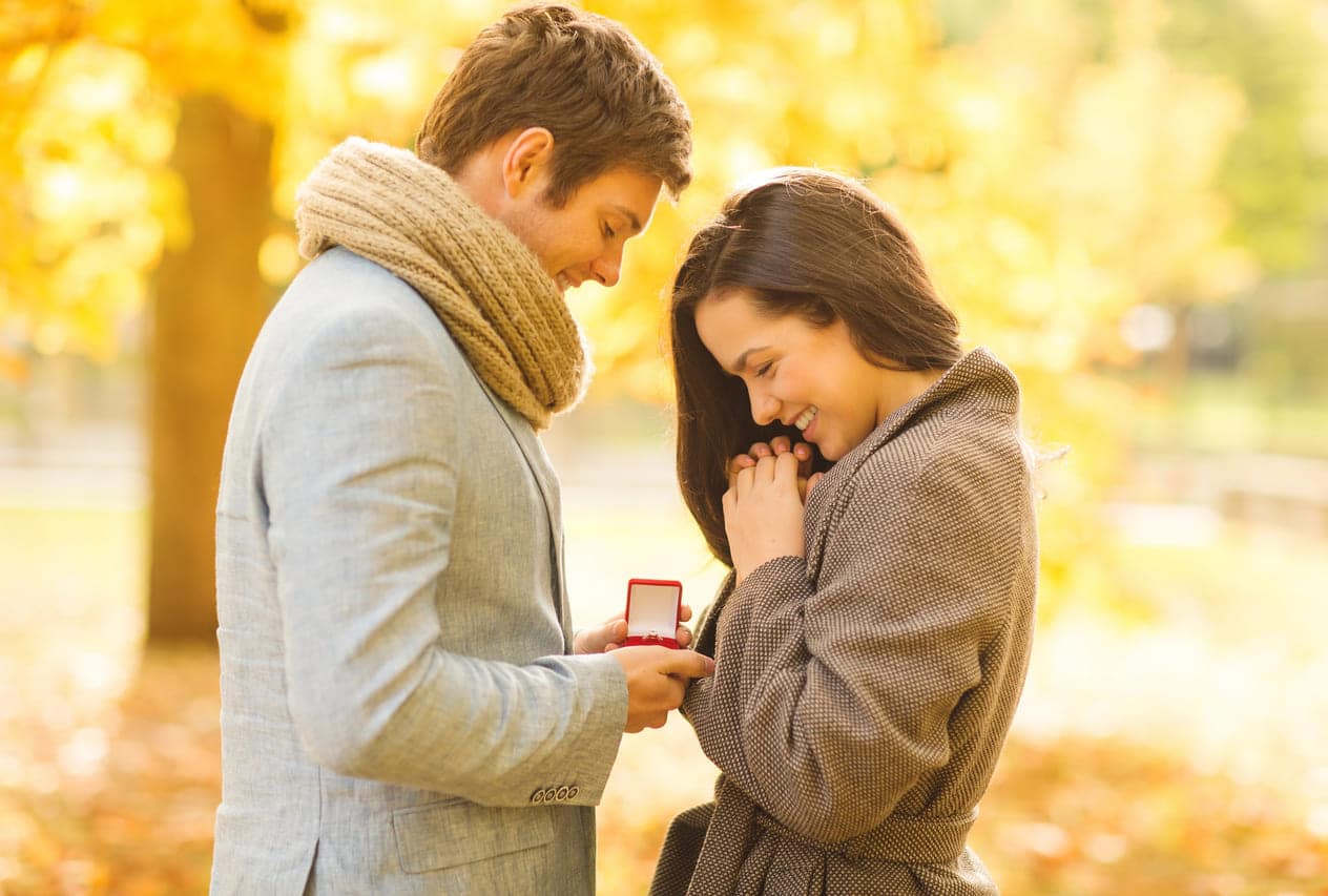 Man proposing to woman with a ring in autumn park