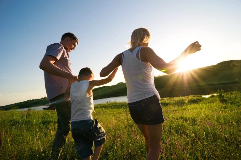 Family walking together in a field during sunset