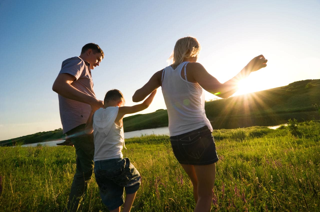 Family walking together in a field during sunset
