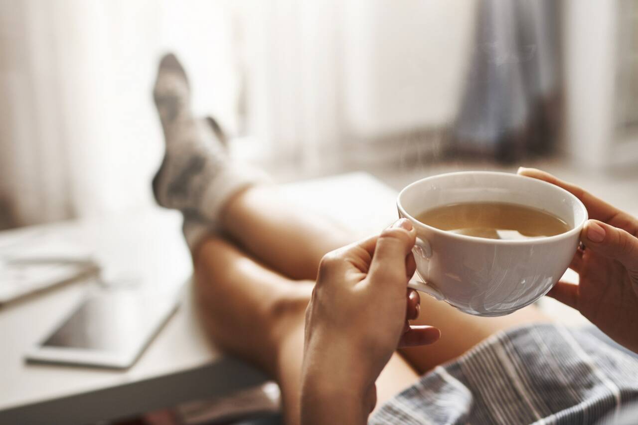 Person relaxing with a cup of tea while sitting