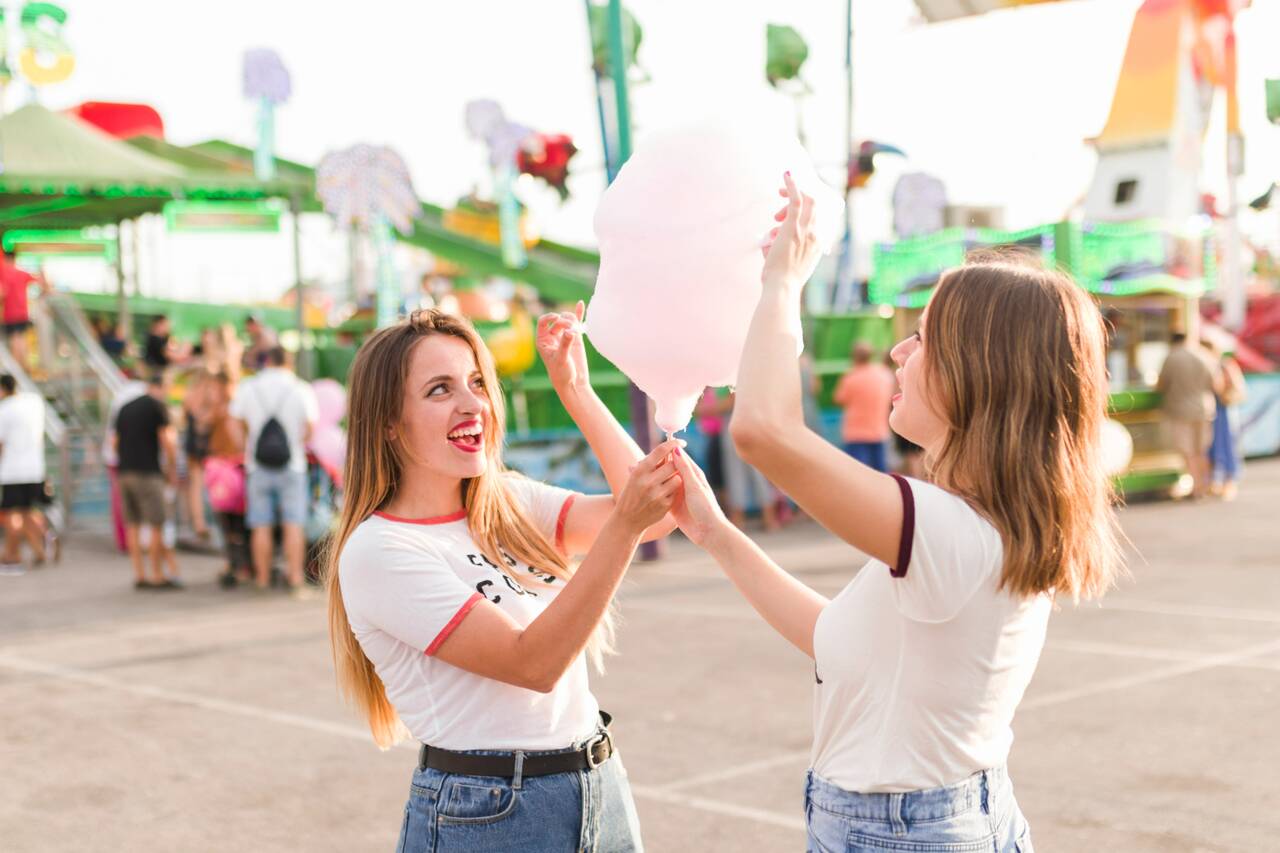 Two women sharing cotton candy at a carnival