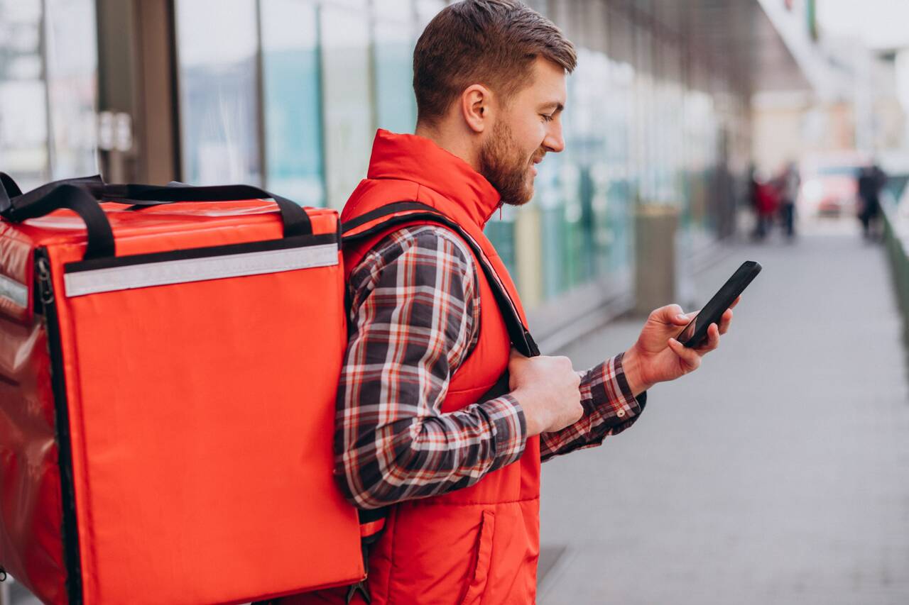 Delivery person in red uniform checking phone