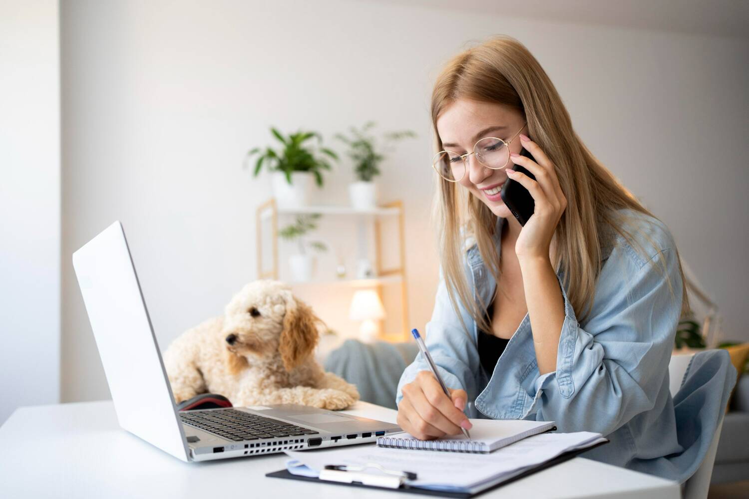 Woman working on laptop with a dog nearby