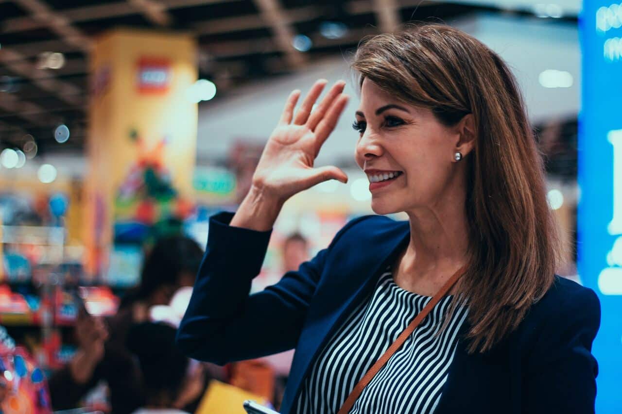 woman waving and smiling inside a store