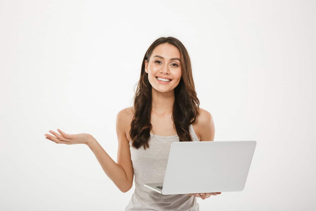 Smiling woman holding a laptop and gesturing