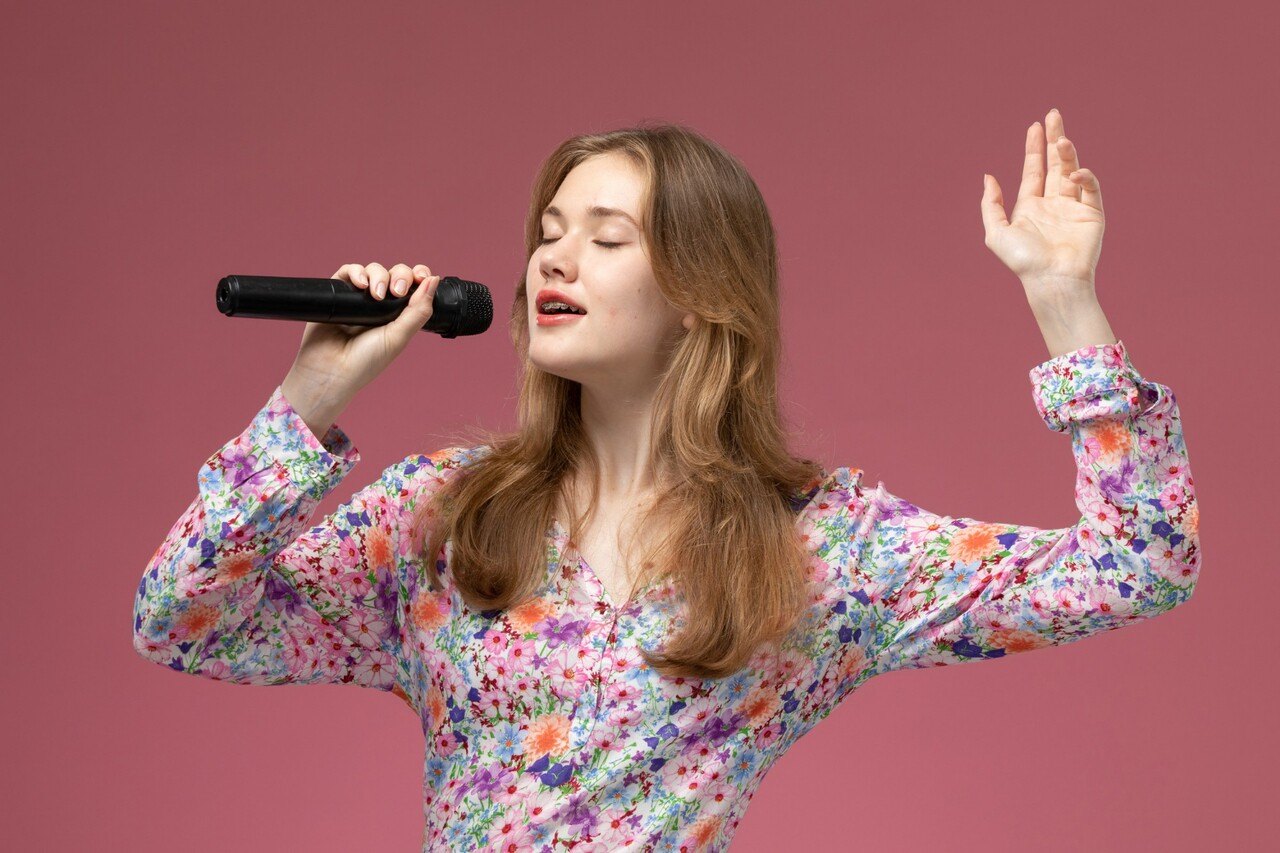 Woman in floral shirt singing with a microphone