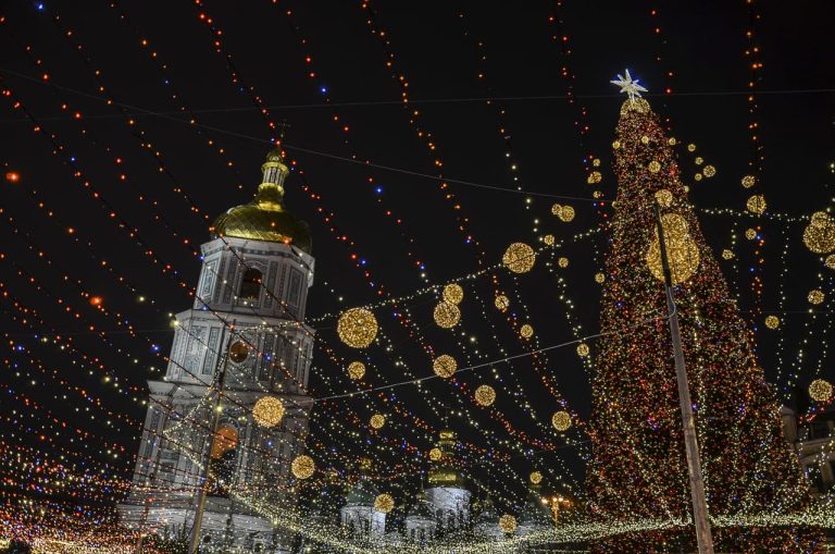 Christmas lights draped over a church and large tree