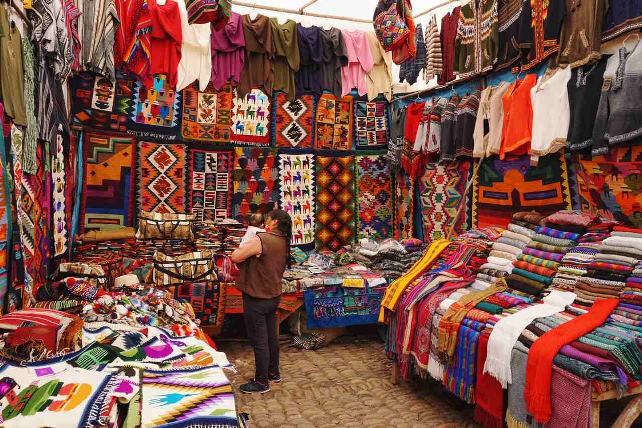 Market stall displaying colorful woven textiles and clothing