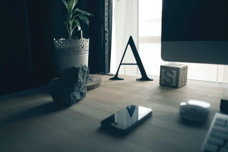Desk with decorative letter A, plant, and smartphone
