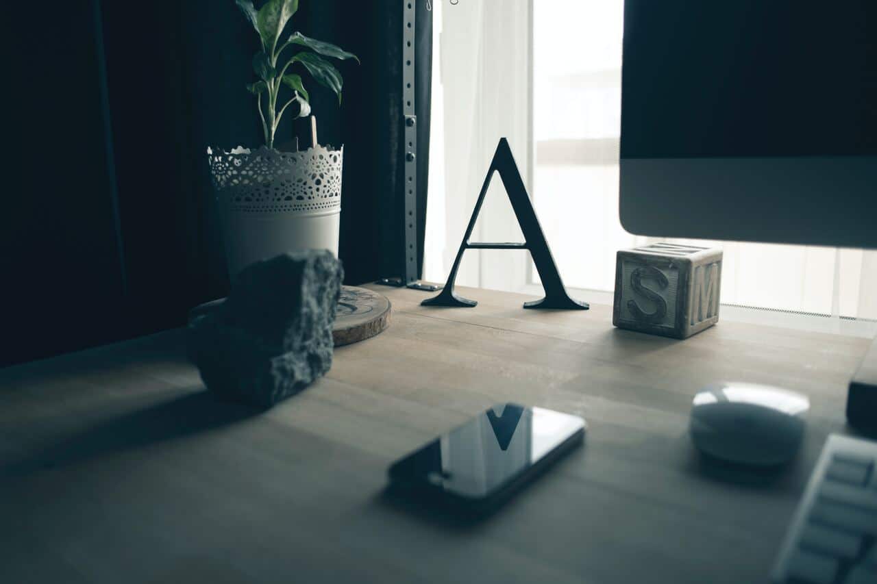 Desk with decorative letter A, plant, and smartphone
