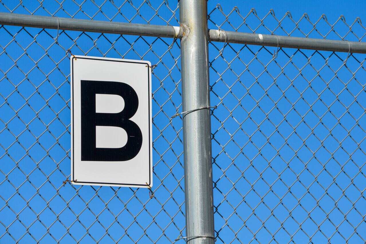 Letter B sign attached to a chain-link fence