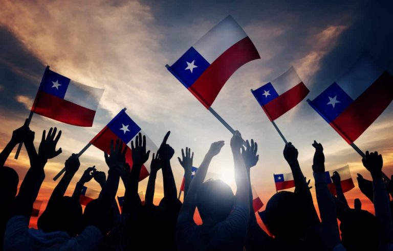 Silhouettes waving Chilean flags during sunset celebration