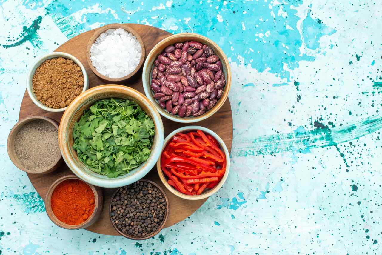 Bowls of spices, herbs, beans, and vegetables on tray