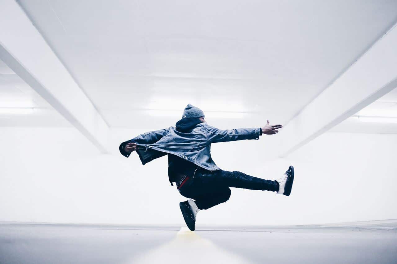 Person mid-air performing a dance move in white room