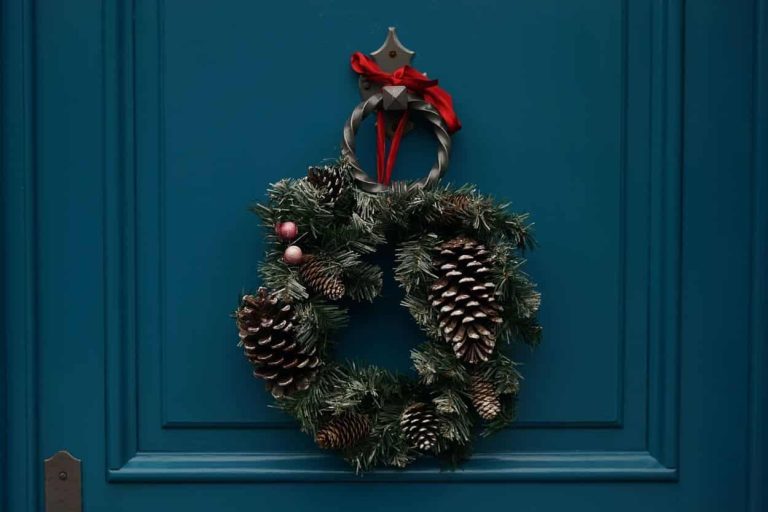 Christmas wreath with pinecones and red bow on a blue door