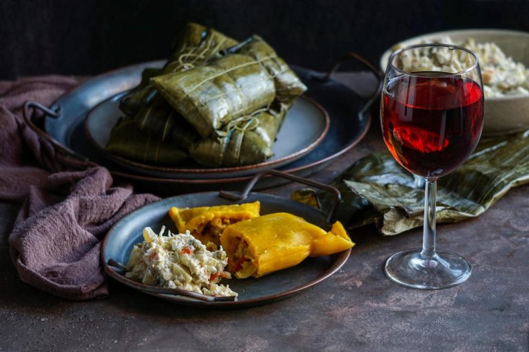 A plate of tamales and salad next to a glass of wine.